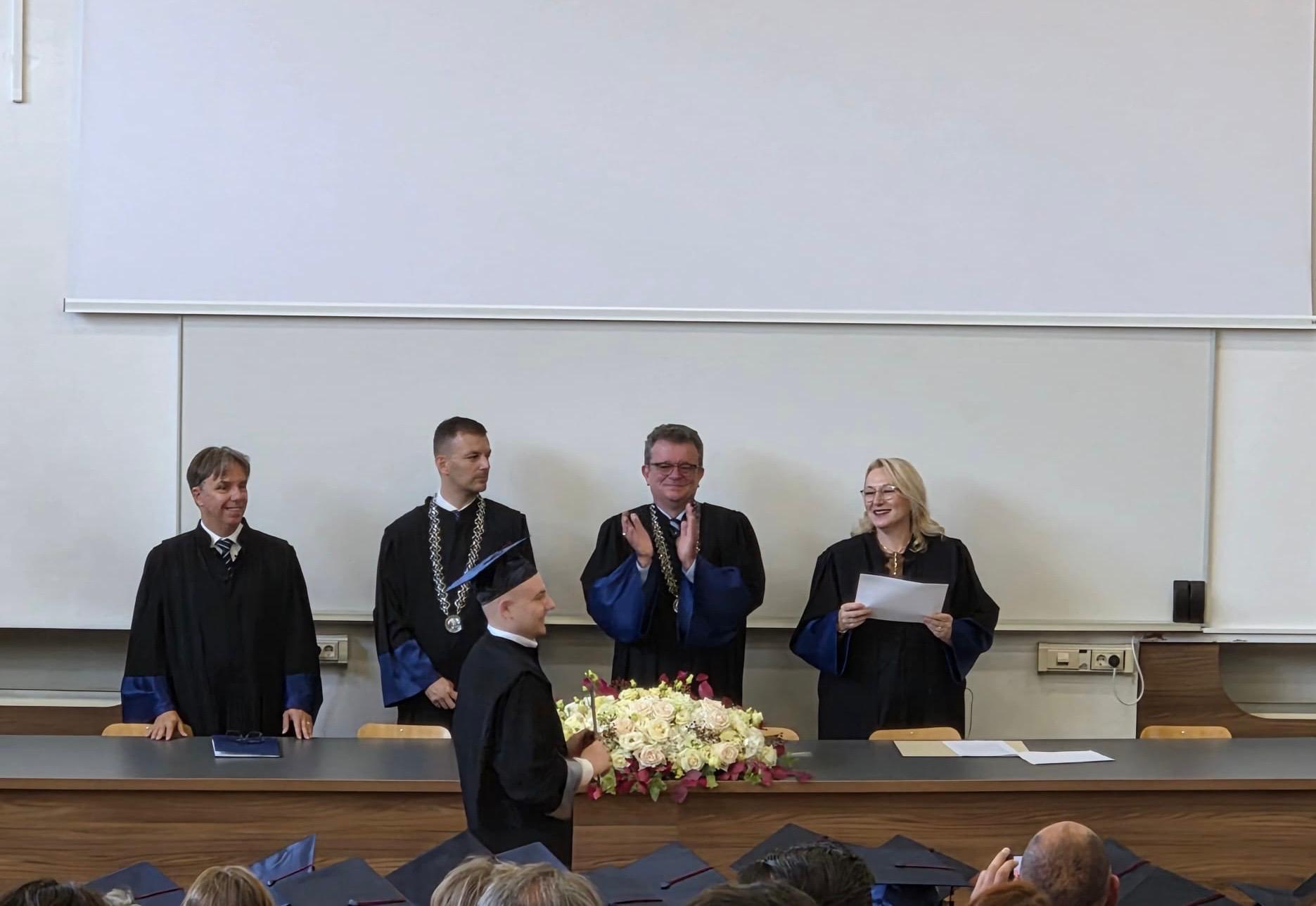 A graduate receiving his degree before the academic board at the promotion ceremony